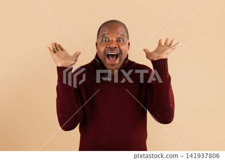 Happy mature African American man celebrating with raised hands and excited expression Happy mature African American man celebrating with raised hands and excited expression 141937806