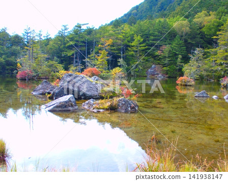 A pond in the mountains where the autumn leaves have begun to change color. A pond in the mountains where the autumn leaves have begun to change color. 141938147
