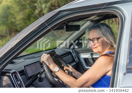 Middle-aged woman is sitting in a new modern car. Middle-aged woman is sitting in a new modern car. 141938482