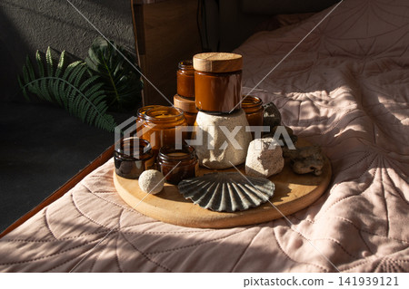 Candle Amber Jars with Wooden Lids on Bed. Candles Glass Jars and Bottles with Natural Elements Candle Amber Jars with Wooden Lids on Bed. Candles Glass Jars and Bottles with Natural Elements 141939121