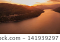 Aerial view of Zhinvali reservoir surrounded by green mountain hills illuminated by warm golden sunset light in Georgia scenic travel destination landscape photo 141939297