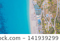 Aerial top down view of Kathisma beach shoreline with bright turquoise Ionian sea water umbrellas resorts and winding road Lefkada island Greece travel photo 141939299