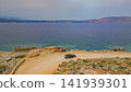 Black car driving on dirt coastal road along sea with rocky shore and mountains in distance road trip travel exploration concept Greece landscape photo 141939301