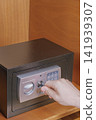 Man hand inserting emergency override master key into electronic safe box lock inside wooden hotel wardrobe close up commercial security concept stock photo 141939307