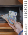 Man hand taking stack of euro banknotes out of open small electronic safe box inside wooden wardrobe close up wealth security storage concept stock photo 141939311