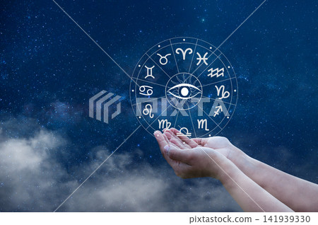Cupped hands holding an astrology zodiac wheel with all seeing eye, under a starry Milky Way sky. Cupped hands holding an astrology zodiac wheel with all seeing eye, under a starry Milky Way sky. 141939330
