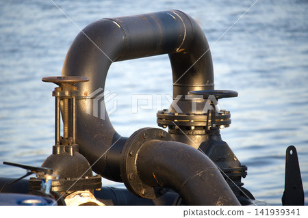 Industrial Black Pipes and Valves at Waterfront Dock With Metal Flanges and Fittings Industrial Black Pipes and Valves at Waterfront Dock With Metal Flanges and Fittings 141939341
