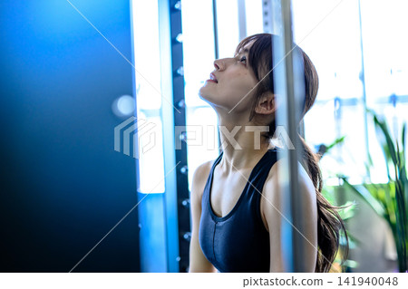 一位女士坐在史密斯機上,調整呼吸;健身房鍛鍊畫面;健身;晨間色彩藝術。 一位女士坐在史密斯機上,調整呼吸;健身房鍛鍊畫面;健身;晨間色彩藝術。 141940048