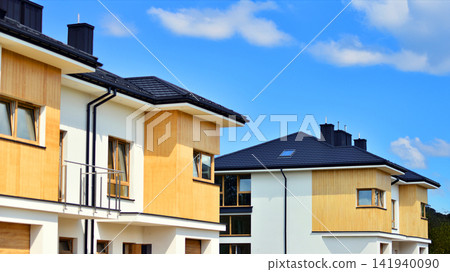 New single family houses in a new development area. Residential homes with modern facade. The real estate market in the suburbs. Terraced family homes in newly developed housing estate. New single family houses in a new development area. Residential homes with modern facade. The real estate market in the suburbs. Terraced family homes in newly developed housing estate. 141940090