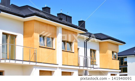 New single family houses in a new development area. Residential homes with modern facade. The real estate market in the suburbs. Terraced family homes in newly developed housing estate. New single family houses in a new development area. Residential homes with modern facade. The real estate market in the suburbs. Terraced family homes in newly developed housing estate. 141940091