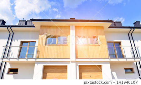 New single family houses in a new development area. Residential homes with modern facade. The real estate market in the suburbs. Terraced family homes in newly developed housing estate. New single family houses in a new development area. Residential homes with modern facade. The real estate market in the suburbs. Terraced family homes in newly developed housing estate. 141940107