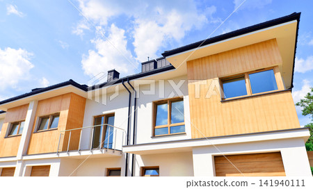 New single family houses in a new development area. Residential homes with modern facade. The real estate market in the suburbs. Terraced family homes in newly developed housing estate. New single family houses in a new development area. Residential homes with modern facade. The real estate market in the suburbs. Terraced family homes in newly developed housing estate. 141940111