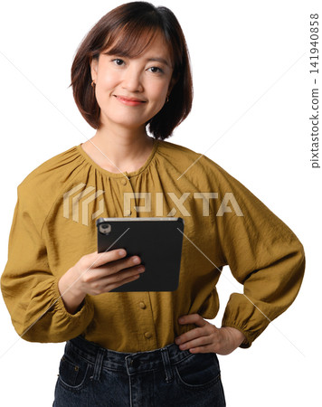 Asian woman holding tablet and smiling with confident professional expression in mustard blouse against transparent background 141940858