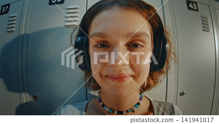 Young Girl in Headphones While Listening to Music in School Hallway Young Girl in Headphones While Listening to Music in School Hallway 141941017