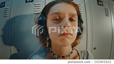 Young Girl in Headphones While Listening to Music in School Hallway Young Girl in Headphones While Listening to Music in School Hallway 141941022