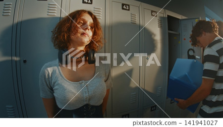 Girl With Short Curly Hair Standing Against School Lockers, Lost in Own Thoughts Girl With Short Curly Hair Standing Against School Lockers, Lost in Own Thoughts 141941027