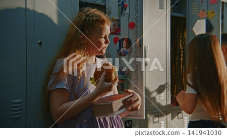 Young Girl Standing Beside Personalized Locker Eating Homemade Sandwich Young Girl Standing Beside Personalized Locker Eating Homemade Sandwich 141941030