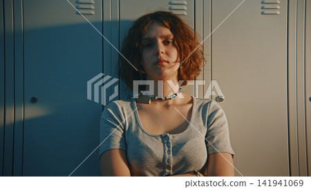 Anxious Teen Female Student Feeling Distressed inside School Locker Room Anxious Teen Female Student Feeling Distressed inside School Locker Room 141941069