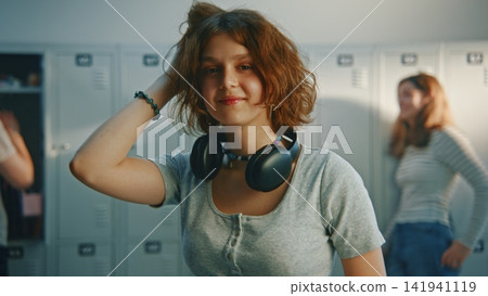 Happy Teenage Girl with Headphones Smiling by School Lockers Happy Teenage Girl with Headphones Smiling by School Lockers 141941119