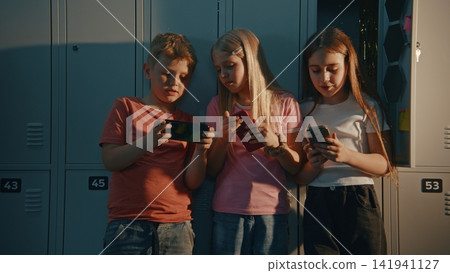 Boy and Two Girls Busy Texting, Playing Mobile Games, or Scrolling Through Social Media Boy and Two Girls Busy Texting, Playing Mobile Games, or Scrolling Through Social Media 141941127