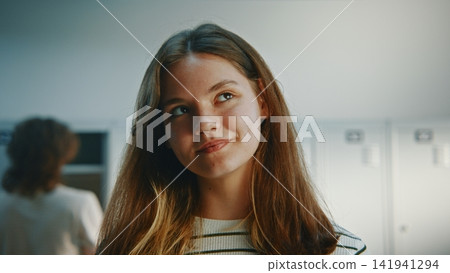 Cheerful Long Haired Teenage Girl Standing Near School Lockers and Smiling Cheerful Long Haired Teenage Girl Standing Near School Lockers and Smiling 141941294