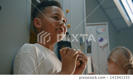 Young Student Pauses For Homemade Sandwich Beside Locker Before Returning to Lessons Young Student Pauses For Homemade Sandwich Beside Locker Before Returning to Lessons 141941335