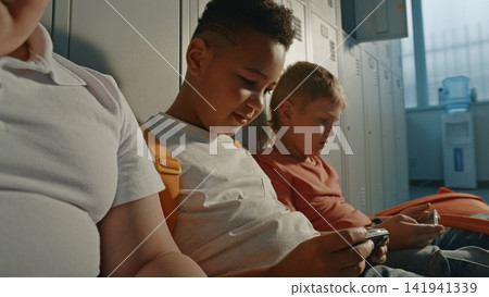 Children Interacting Through Digital Devices while Sitting Beside Lockers Children Interacting Through Digital Devices while Sitting Beside Lockers 141941339
