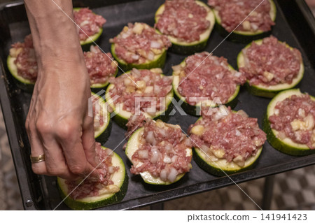 Putting Baking Sheet of Stuffed Zucchini Rounds Inside the Oven Putting Baking Sheet of Stuffed Zucchini Rounds Inside the Oven 141941423