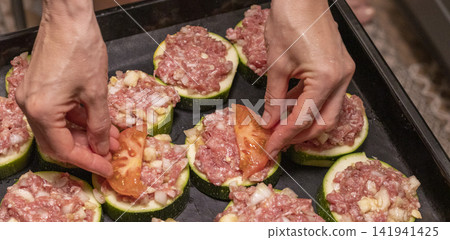 Putting Baking Sheet of Stuffed Zucchini Rounds Inside the Oven Putting Baking Sheet of Stuffed Zucchini Rounds Inside the Oven 141941425