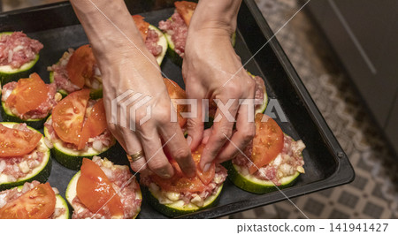Putting Baking Sheet of Stuffed Zucchini Rounds Inside the Oven Putting Baking Sheet of Stuffed Zucchini Rounds Inside the Oven 141941427