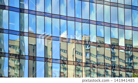 A modern tall building made of steel and glass, housing offices and financial institutions. Glass wall on the facade of the building. A modern tall building made of steel and glass, housing offices and financial institutions. Glass wall on the facade of the building. 141941485
