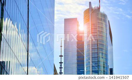 A modern tall building made of steel and glass, housing offices and financial institutions. Glass wall on the facade of the building. A modern tall building made of steel and glass, housing offices and financial institutions. Glass wall on the facade of the building. 141941507