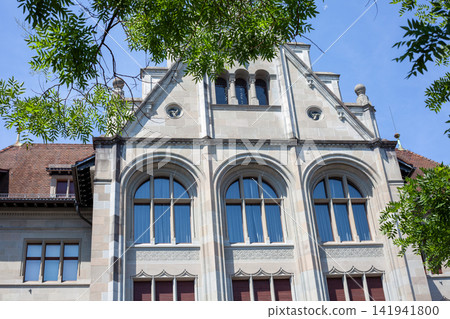 Swiss National Museum Stone Building Facade and Arched Windows View through Tree Leaves in Zurich 141941800