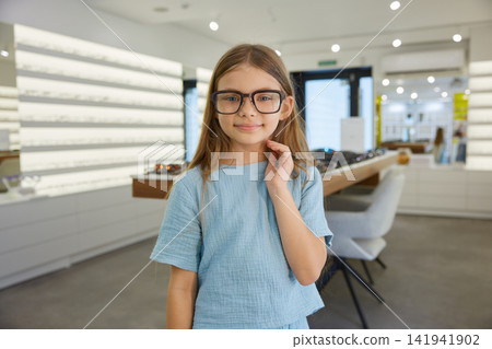 Girl showcasing fashionable glasses in a store Girl showcasing fashionable glasses in a store 141941902