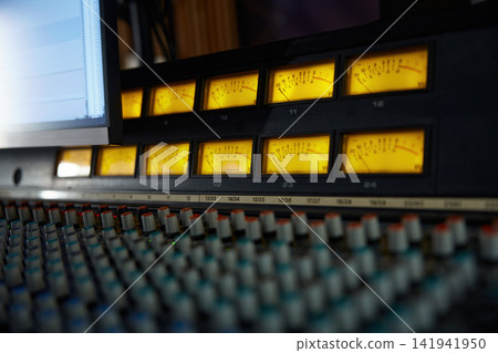 Amber VU meters arranged in rows with knobs for precise audio measurement Amber VU meters arranged in rows with knobs for precise audio measurement 141941950