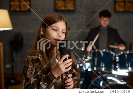 Caucasian girl singing into vintage microphone with dynamic band cooperation Caucasian girl singing into vintage microphone with dynamic band cooperation 141941969
