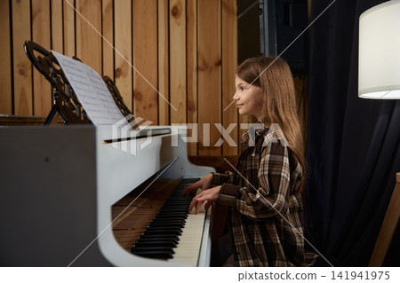 Teenage girl in cozy studio passionately performing with sheet music and warm lighting Teenage girl in cozy studio passionately performing with sheet music and warm lighting 141941975