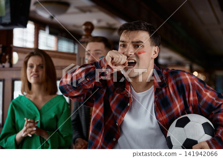 Man passionately celebrates goal in bustling pub filled with friends and excitement 141942066