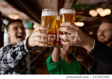 Group of colleagues enthusiastically clinking beer glasses in a pub Group of colleagues enthusiastically clinking beer glasses in a pub 141942088