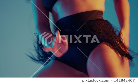 Professional woman dancing sexy twerk choreography in black fringe waist shorts, colorful studio Professional woman dancing sexy twerk choreography in black fringe waist shorts, colorful studio 141942407