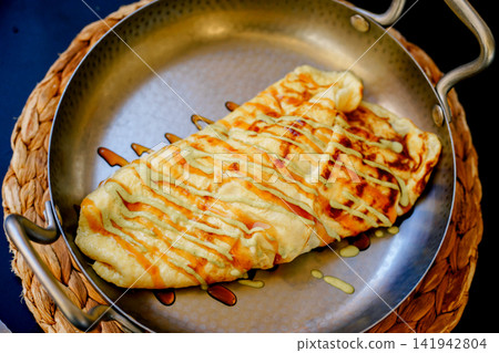 Fresh stuffed omelet served in a metal pan with colorful sauces at a restaurant. Concept of breakfast, comfort food, dining and Mediterranean cuisine Fresh stuffed omelet served in a metal pan with colorful sauces at a restaurant. Concept of breakfast, comfort food, dining and Mediterranean cuisine 141942804