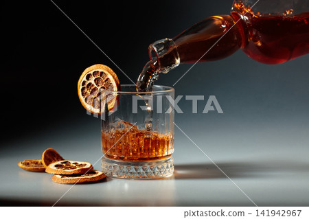 Whiskey is poured into a in crystal glass. Whiskey is poured into a in crystal glass. 141942967