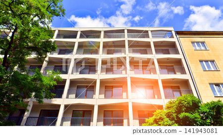 Modern residential building with new apartments in a green residential area. Eco architecture. Green tree and new apartment building. The harmony of nature and modernity. Modern residential building with new apartments in a green residential area. Eco architecture. Green tree and new apartment building. The harmony of nature and modernity. 141943081