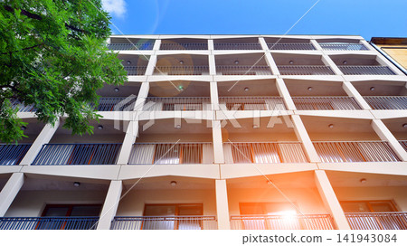 Modern residential building with new apartments in a green residential area. Eco architecture. Green tree and new apartment building. The harmony of nature and modernity. Modern residential building with new apartments in a green residential area. Eco architecture. Green tree and new apartment building. The harmony of nature and modernity. 141943084