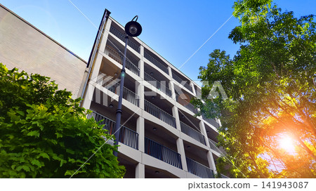Modern residential building with new apartments in a green residential area. Eco architecture. Green tree and new apartment building. The harmony of nature and modernity. Modern residential building with new apartments in a green residential area. Eco architecture. Green tree and new apartment building. The harmony of nature and modernity. 141943087