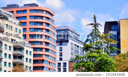 Modern residential building with new apartments in a green residential area. Eco architecture. Green tree and new apartment building. The harmony of nature and modernity. Modern residential building with new apartments in a green residential area. Eco architecture. Green tree and new apartment building. The harmony of nature and modernity. 141943098