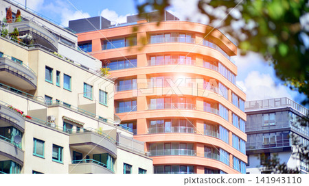 Modern residential building with new apartments in a green residential area. Eco architecture. Green tree and new apartment building. The harmony of nature and modernity. Modern residential building with new apartments in a green residential area. Eco architecture. Green tree and new apartment building. The harmony of nature and modernity. 141943110