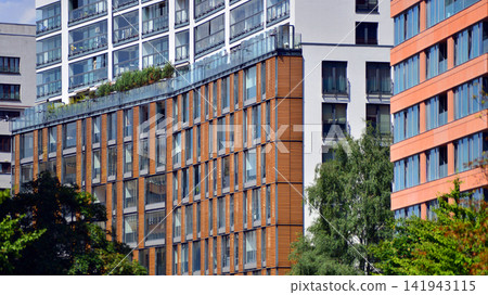 Modern residential building with new apartments in a green residential area. Eco architecture. Green tree and new apartment building. The harmony of nature and modernity. Modern residential building with new apartments in a green residential area. Eco architecture. Green tree and new apartment building. The harmony of nature and modernity. 141943115