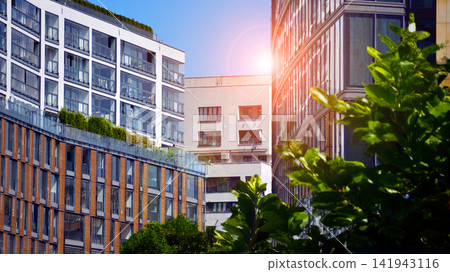 Modern residential building with new apartments in a green residential area. Eco architecture. Green tree and new apartment building. The harmony of nature and modernity. Modern residential building with new apartments in a green residential area. Eco architecture. Green tree and new apartment building. The harmony of nature and modernity. 141943116
