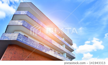 Modern apartment buildings on a sunny day with a blue sky. Facade of a modern apartment building.Glass surface with sunlight. Modern apartment buildings on a sunny day with a blue sky. Facade of a modern apartment building.Glass surface with sunlight. 141943313